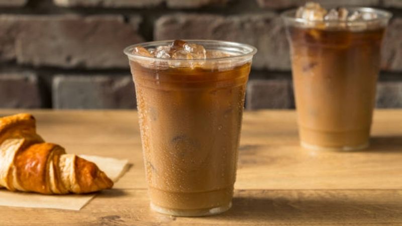 Cà phê sữa đá thơm ngon bên bánh croissant giòn tan