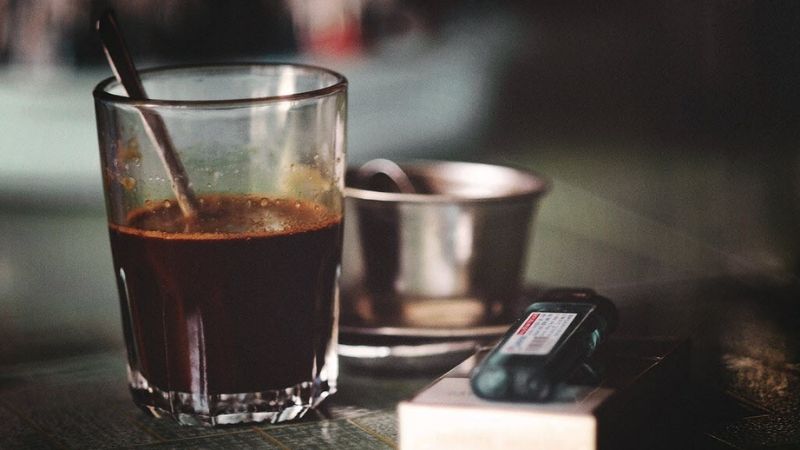 Ly cafe đen bên điện thoại trong quán vắng