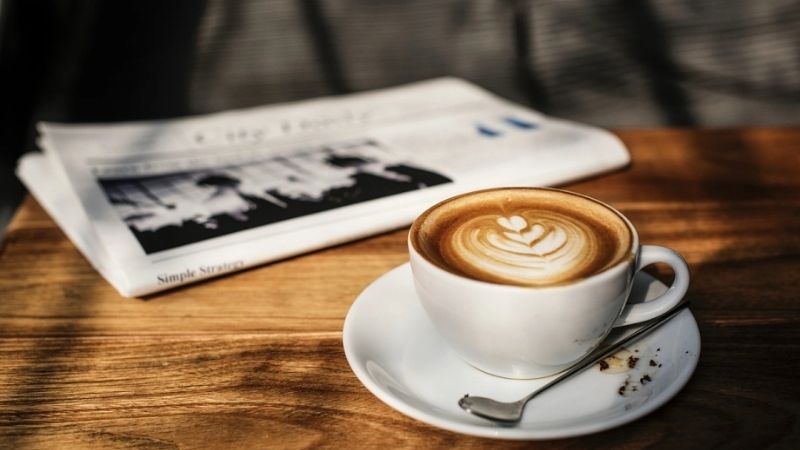 Cappuccino hoàn hảo bên tờ báo buổi sáng yên tĩnh
