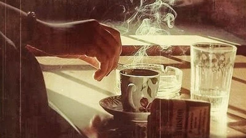 Tay nhấc tách cafe trong ánh sáng vàng chiều tà