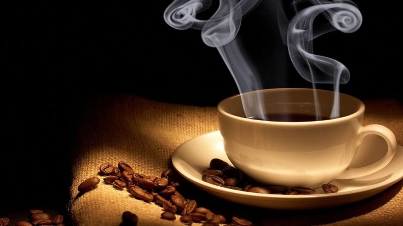 Cà phê nóng bốc khói cùng hạt cà phê rang xay
