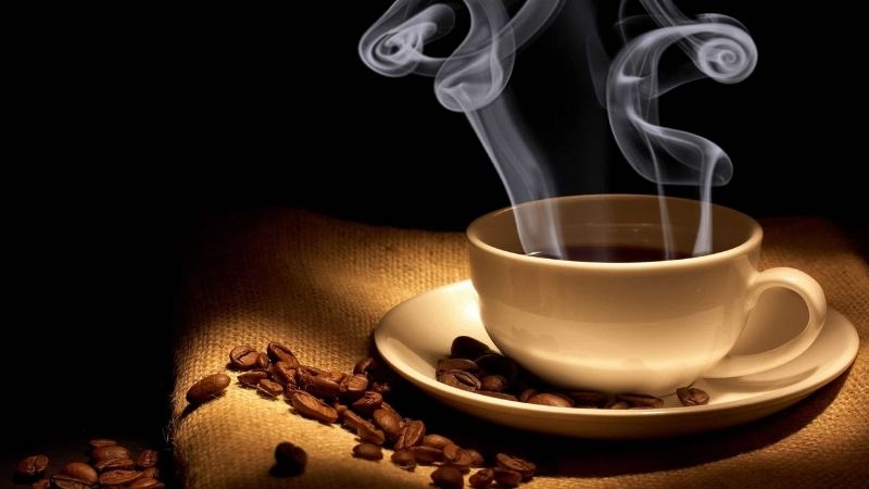 Ly cà phê vàng bốc khói quyến rũ trong ánh sáng ấm