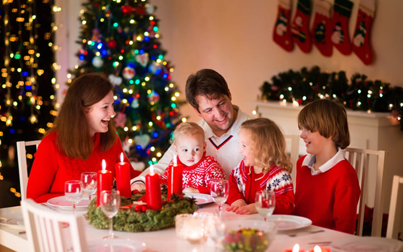 Gia đình quây quần mở quà dưới cây thông