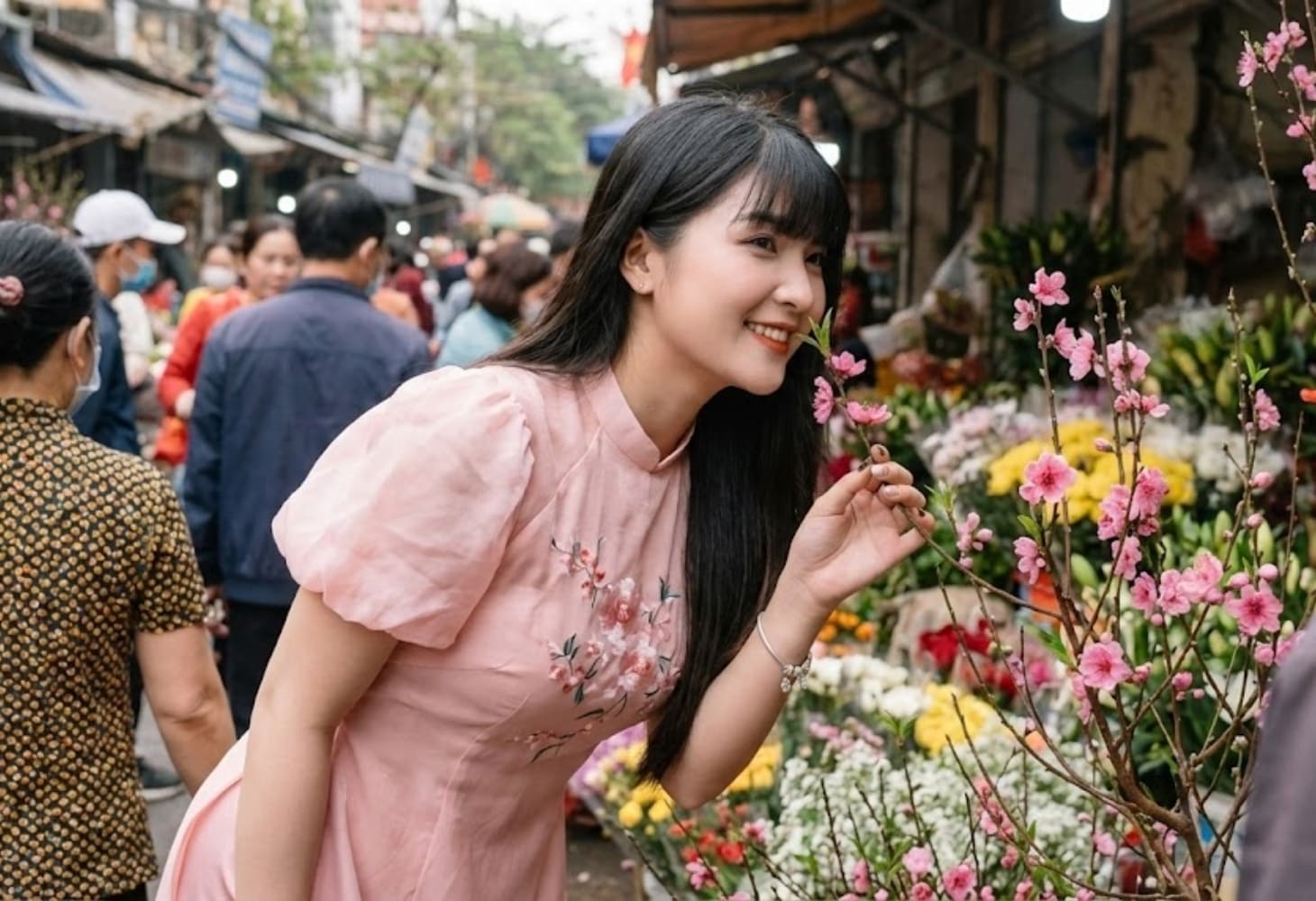 Cô gái mặc áo dài đứng bên nhánh hoa đào xuân