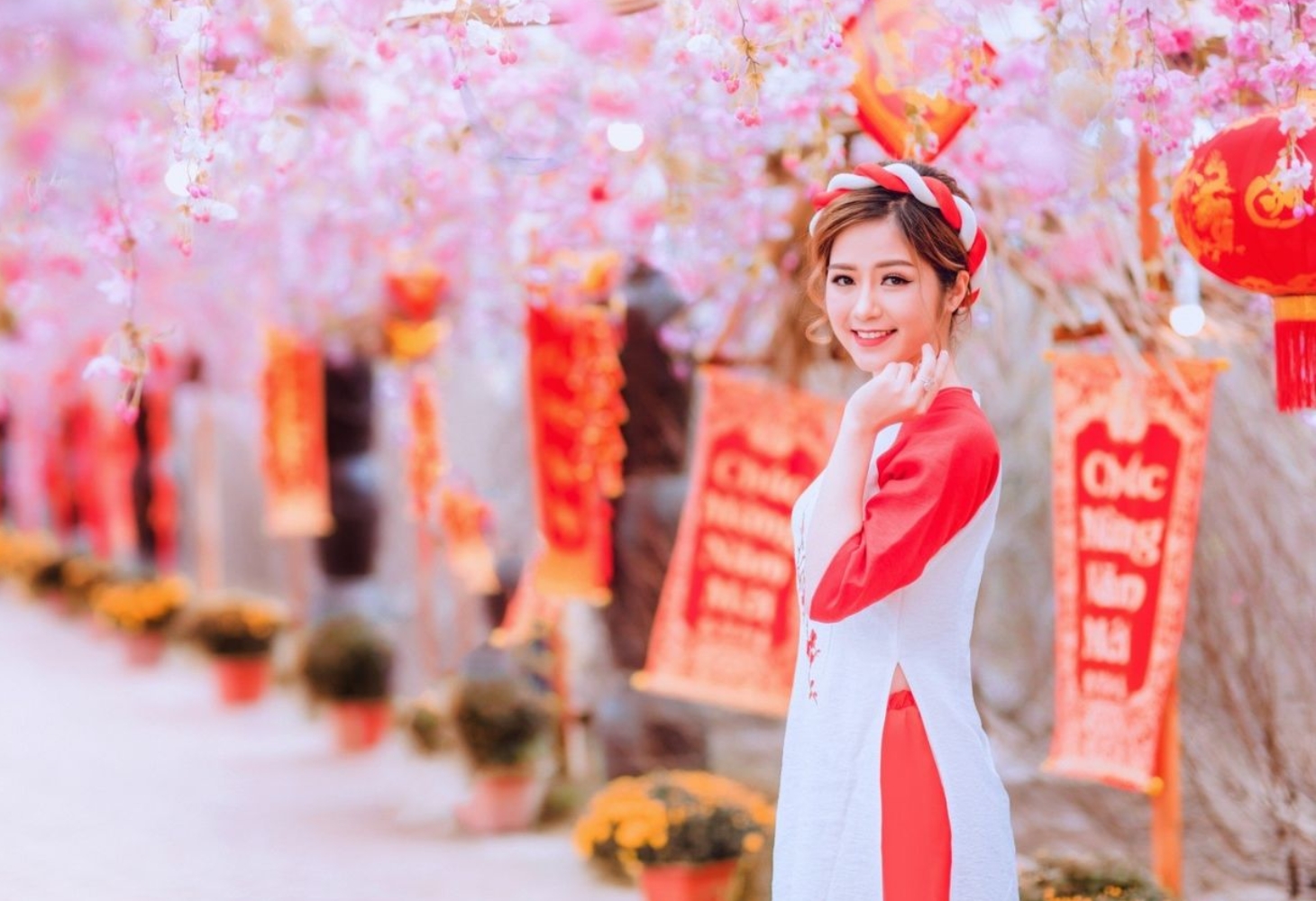 Cô gái tạo dáng áo dài bên câu đối Tết