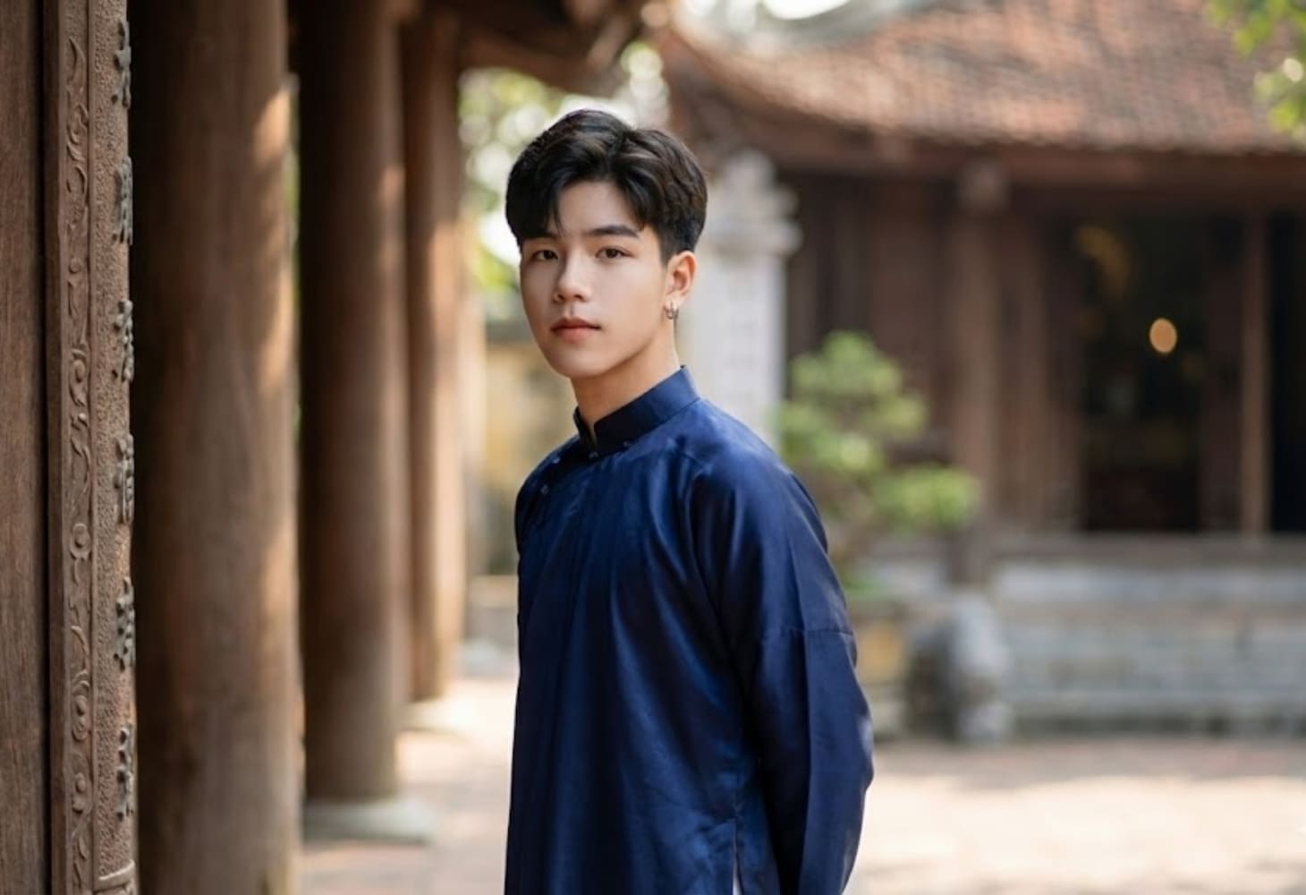 Chàng trai mặc áo dài truyền thống đứng trong cảnh chùa