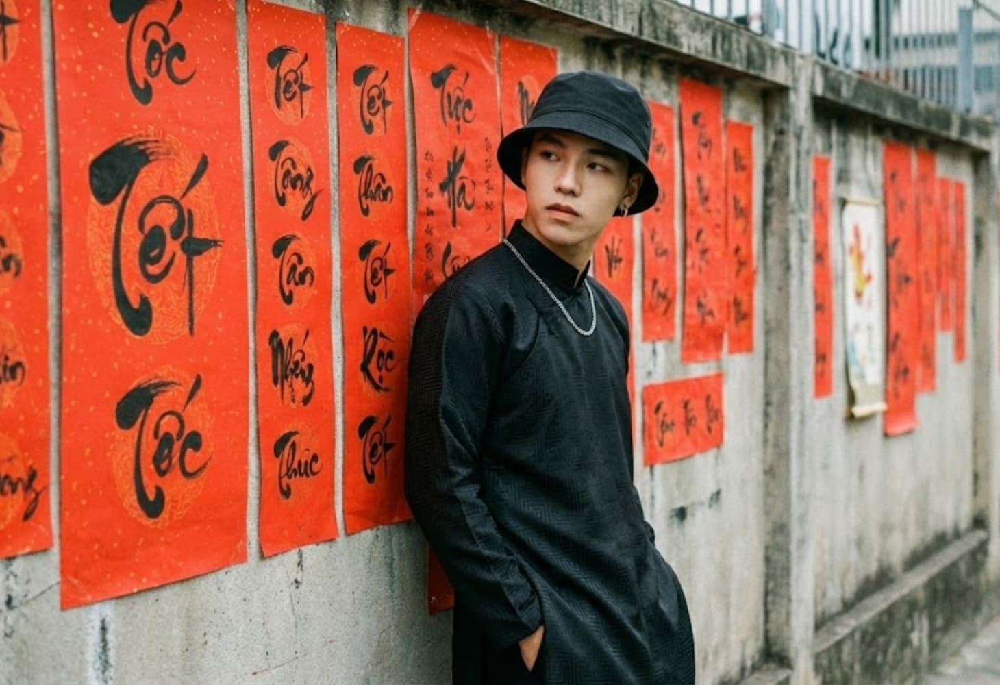 Chàng trai mặc áo dài truyền thống tạo dáng bên câu đối